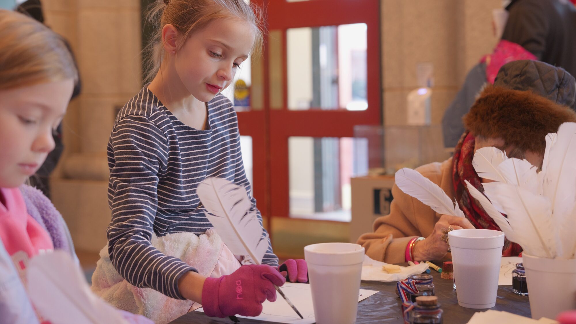 Two girls writing with quill pens