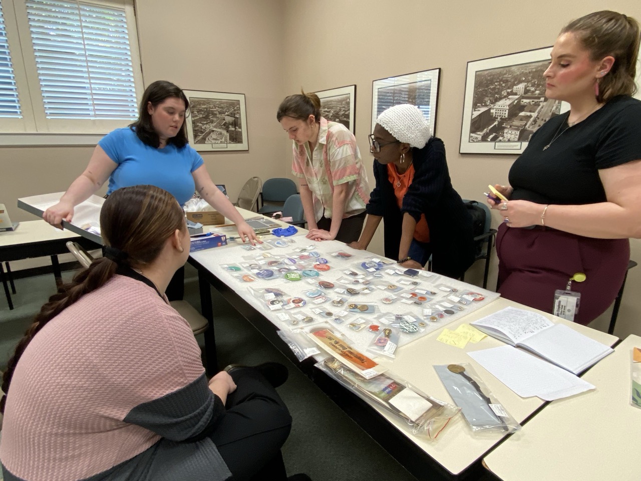 Five students working at button exhibition layout on long table